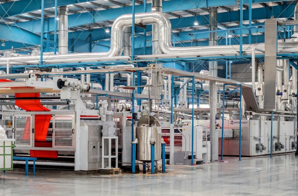 Σύγχρονη βιομηχανική μονάδα παραγωγής με αυτοματοποιημένα μηχανήματα και γραμμή επεξεργασίας υφάσματος σε εργοστάσιο