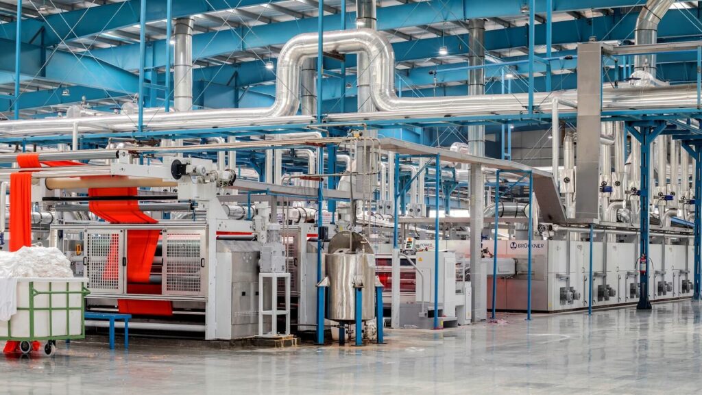 Σύγχρονη βιομηχανική μονάδα παραγωγής με αυτοματοποιημένα μηχανήματα και γραμμή επεξεργασίας υφάσματος σε εργοστάσιο