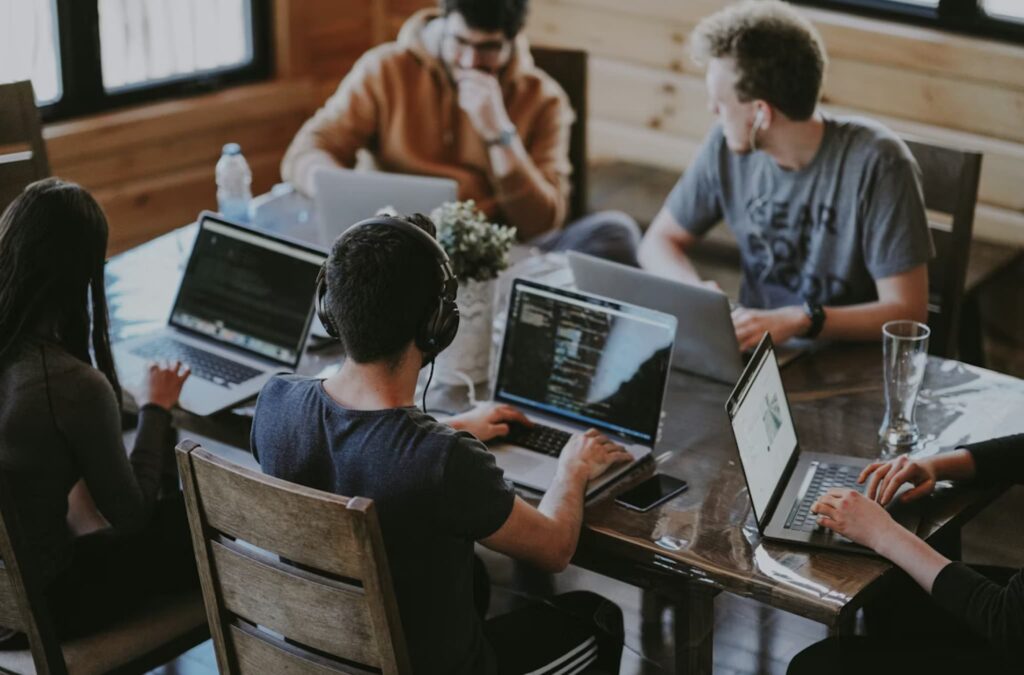 A group of young professionals collaborating around a table, representing the new generation of graduate entrepreneurs supported by the "Ξεκινώ Επιχειρηματικά" ESPA 2021–2027 grant programme.